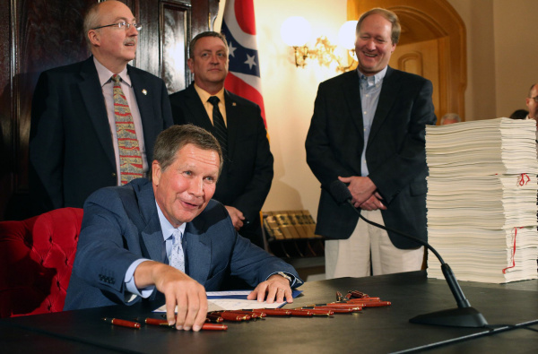 Ohio Governor John Kasich smiles while signing the new two-year Ohio budget during a bill signing ceremony at the Ohio Statehouse in Columbus, Ohio on June 30, 2013. Kasich had vetoed a piece of the budget that would bar the state's Medicaid program from covering additional low-income residents. (Columbus Dispatch photo by Brooke LaValley)